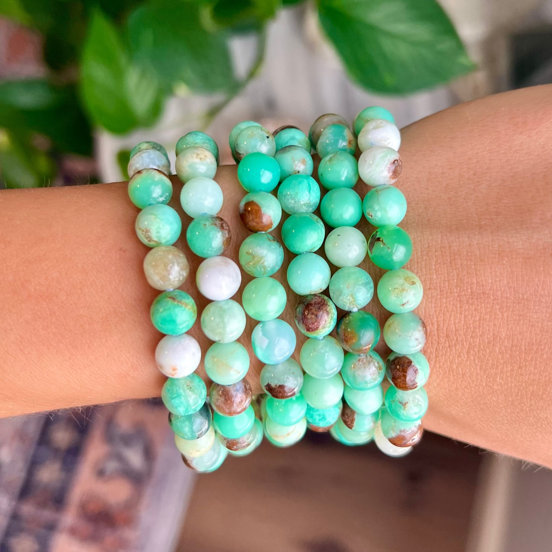 Stack of green beaded bracelets on a wrist with a blurred background